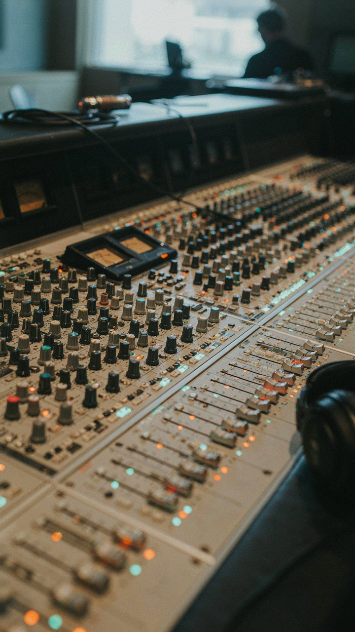 An audio engineer's mixing board with many glowing faders and knobs.