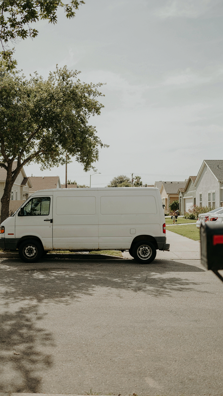 A plain white cargo van blends into a quiet residential street.