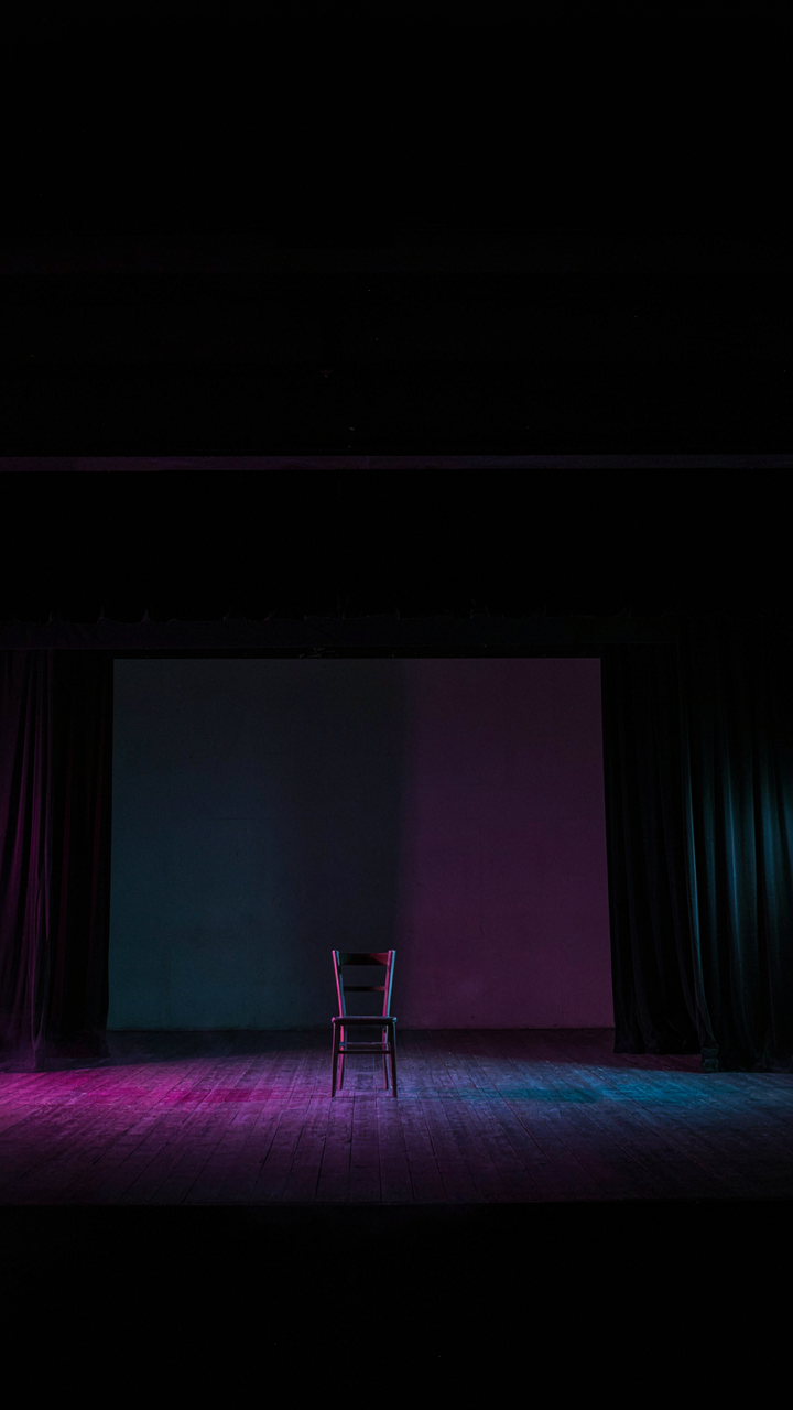 A theater stage with dramatic colored lights casting eerie shadows.