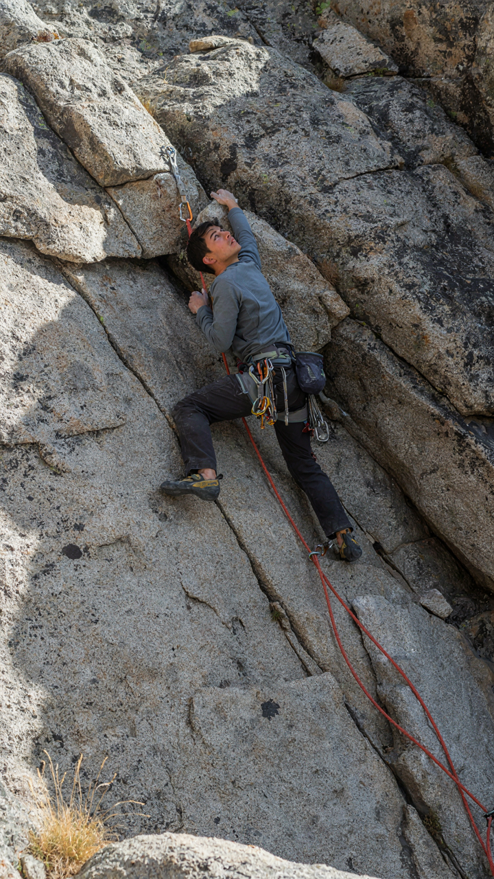 A climber uses ropes and anchors to secure themselves to a rock wall.