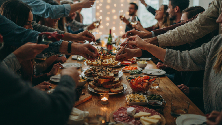 Many people gathered around a small appetizer table, creating a bottleneck at a party.