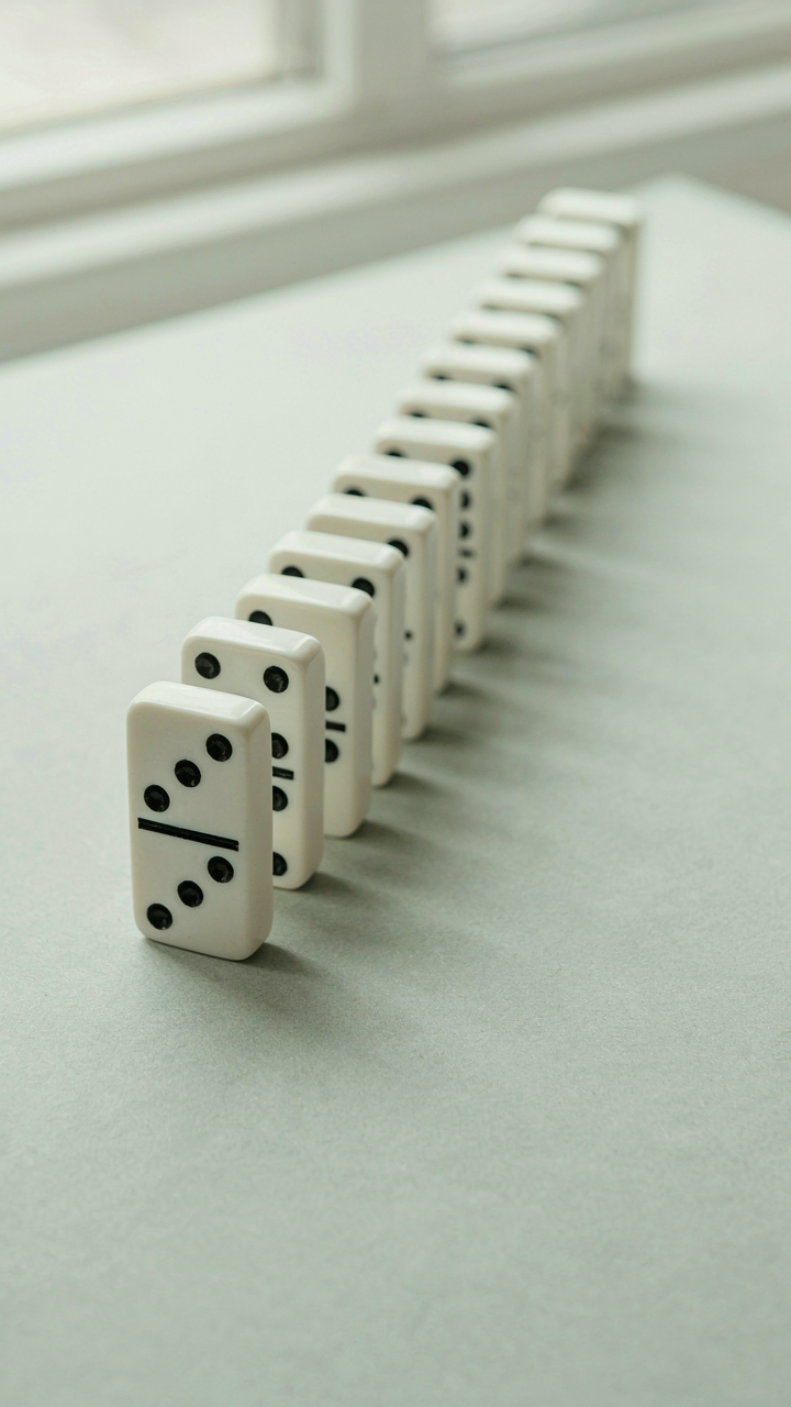 A single standing domino at the end of a long line of fallen dominoes.