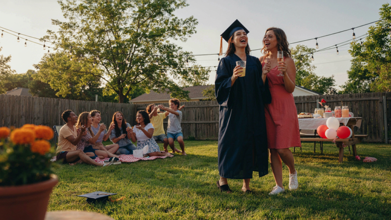 A lively backyard graduation party with young adults celebrating outdoors.