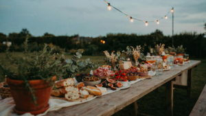 A long, beautifully arranged backyard grazing table at an outdoor evening event.