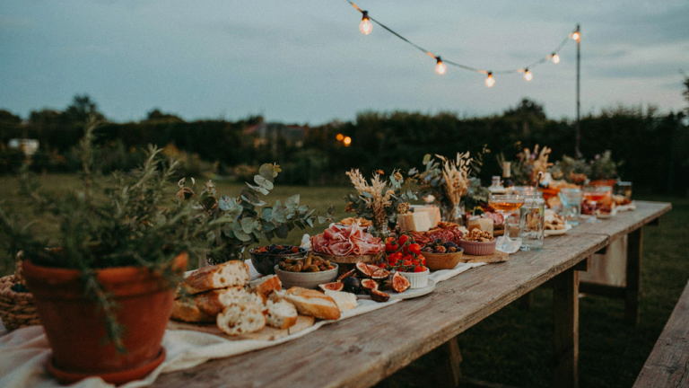 A long, beautifully arranged backyard grazing table at an outdoor evening event.