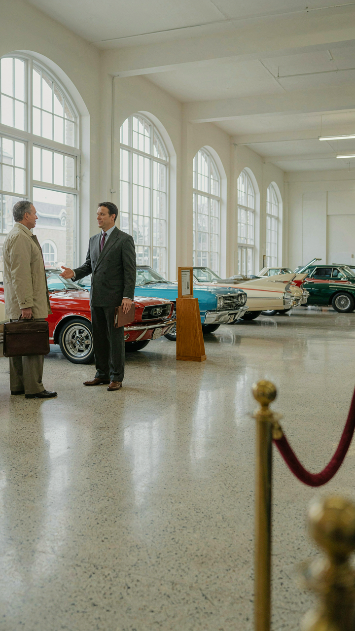 A vintage car showroom with brightly colored cars for sale.