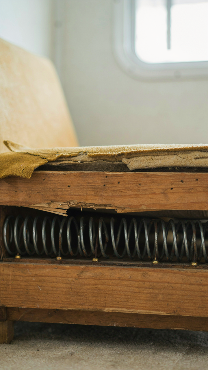 The exposed wooden frame and springs of an old RV couch.