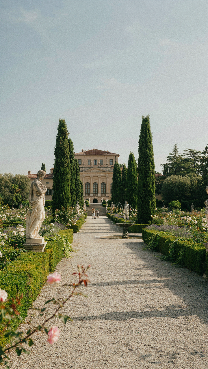 A grand Italian villa garden with intentional landscaping and elegant statues.