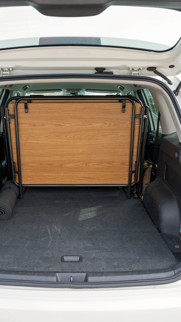 A large folded table fills the entire back space of a small car, taking up much room.