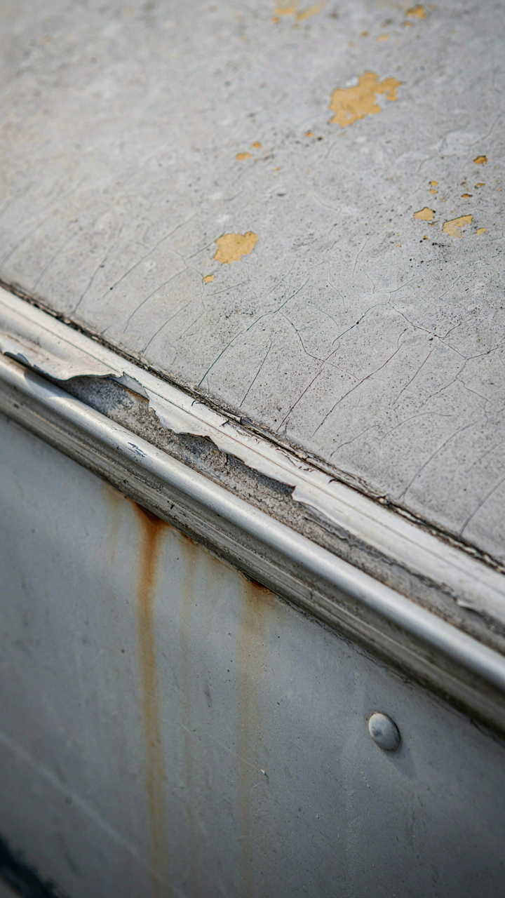 A close-up of a cracked RV roof seam with peeling sealant.
