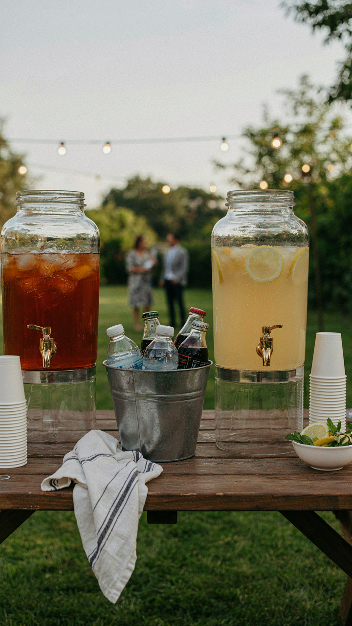 A self serve drink station is set up for guests at a backyard party.
