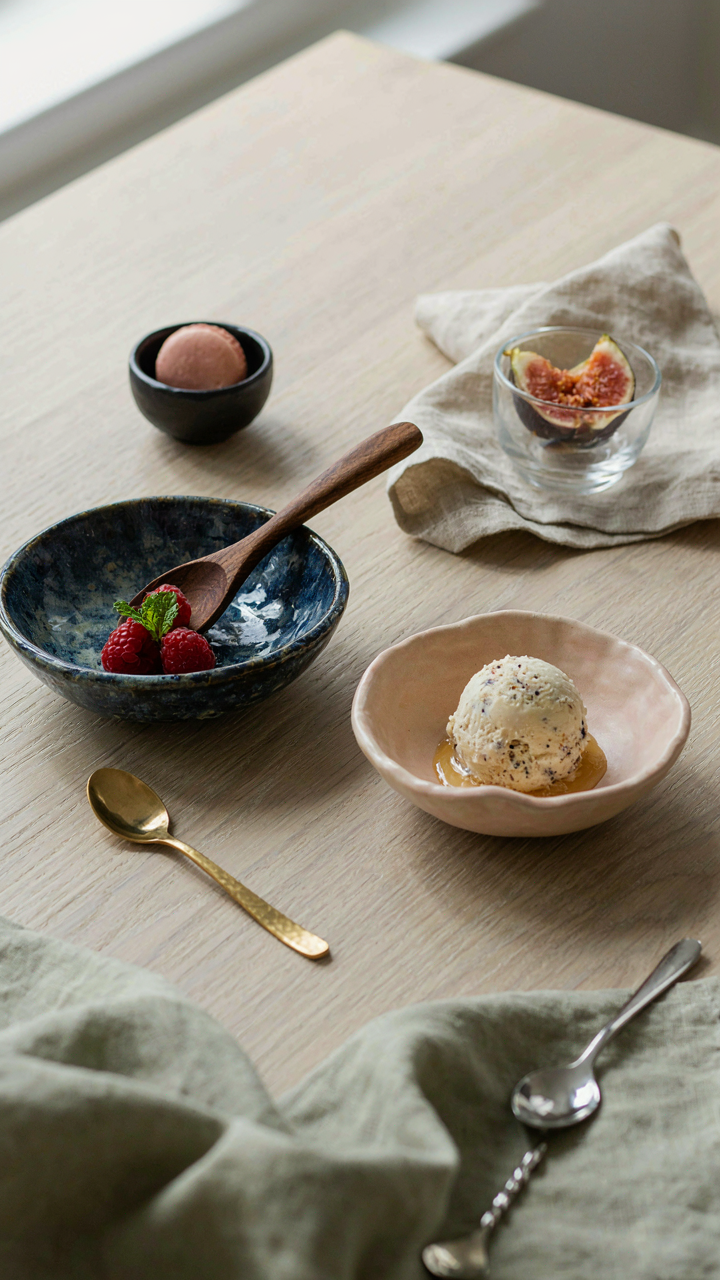 A table holds many uniquely shaped dessert bowls and spoons.