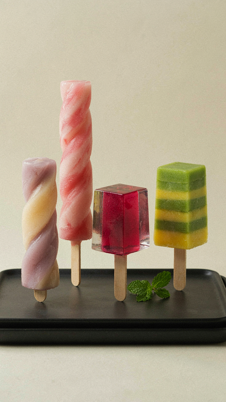 Artisan popsicles in unique, sculptural shapes are displayed on a tray.