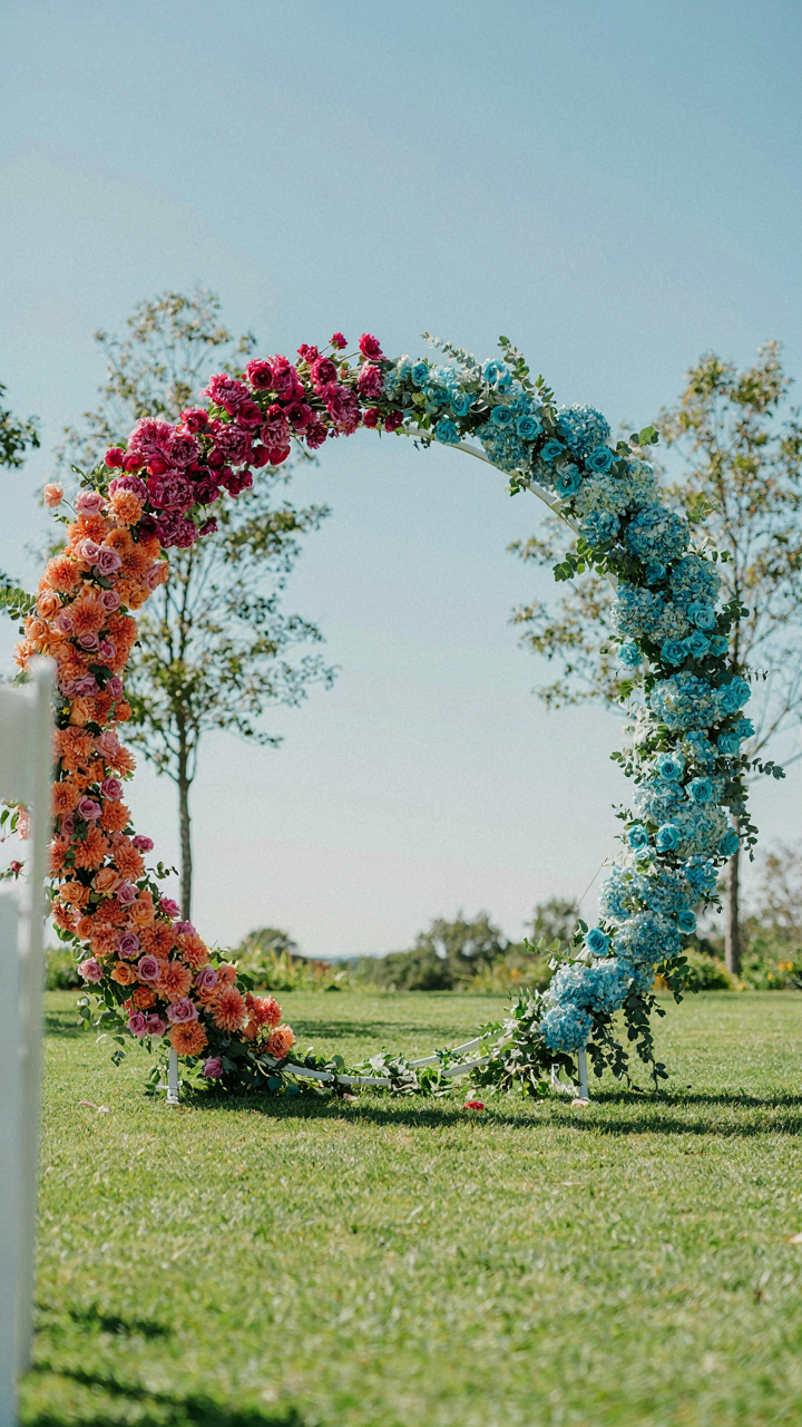 A colorful wedding arch with bright pink, orange, and blue flowers.