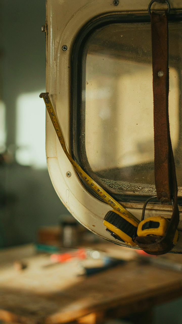 A tape measure bending along the curve of a camper window frame.