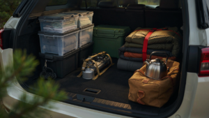 An SUV trunk packed efficiently with camping gear in various containers and secured for travel.