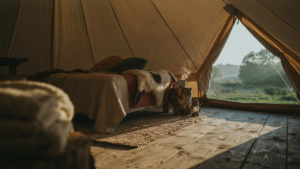 A warm and inviting canvas tent interior, decorated with many cozy textiles and warm lighting.