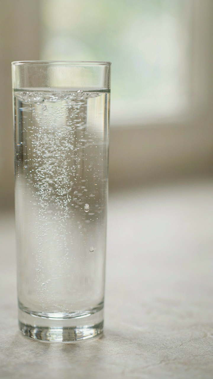 Fine bubbles rise in a clear glass of sparkling water.