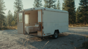 A finished cargo trailer camper conversion with its door open to show the inside.