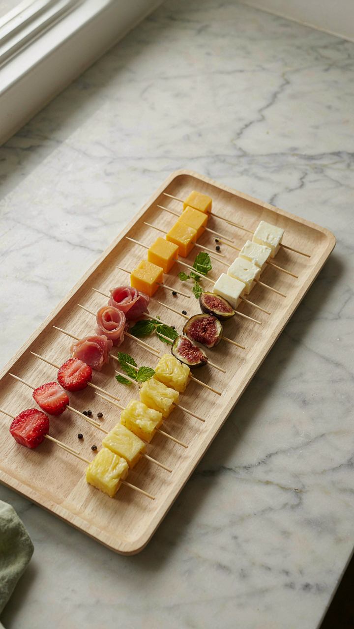 Small skewers with single bites of garden party finger food on a tray.