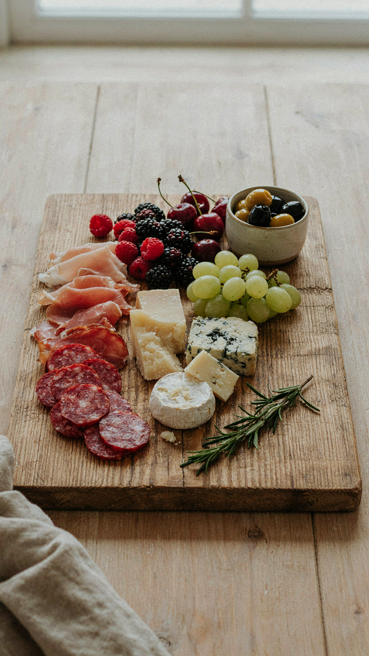 A charcuterie board has meats, cheeses, and berries.