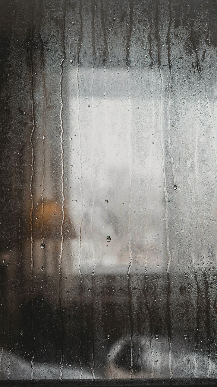 Streaks of condensation drip down a window pane.