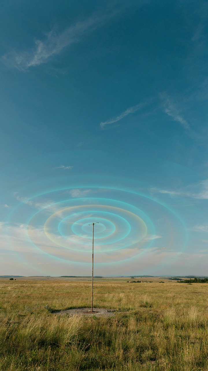 Strong radio waves coming from a small antenna in an open, remote landscape.
