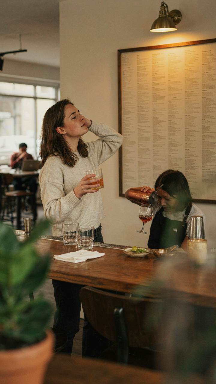 A confused person tries to read a complex sign at a bar.