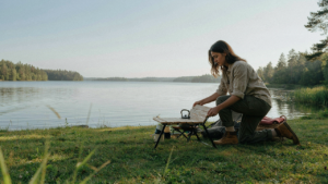 A person quickly sets up a compact, foldable diy camp table by a peaceful lake.