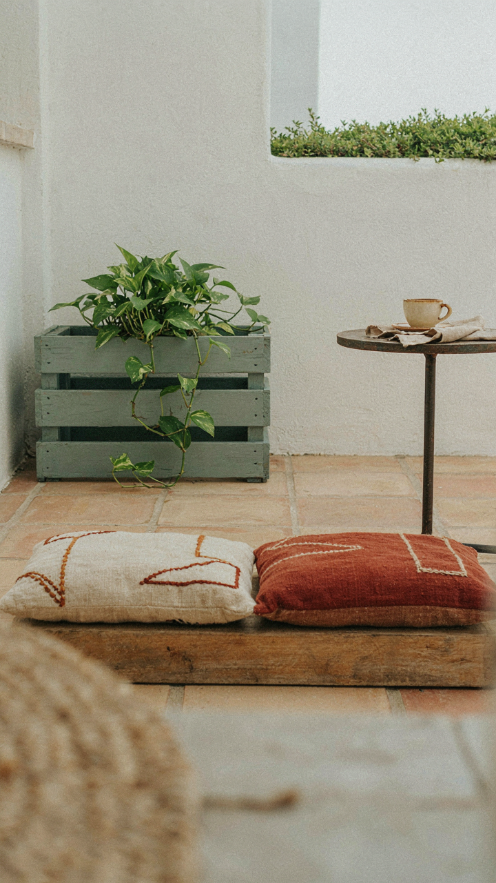 A tiny patio has a stylish planter made from wood pallets and handmade cushions.
