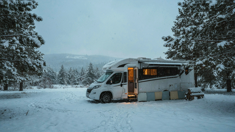 An RV is parked in the snow with diy rv skirting around its base.