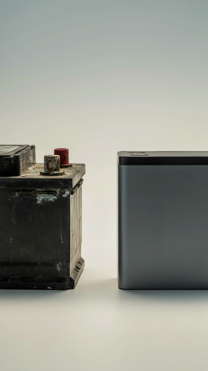 An old lead-acid battery sits next to a new lithium battery.