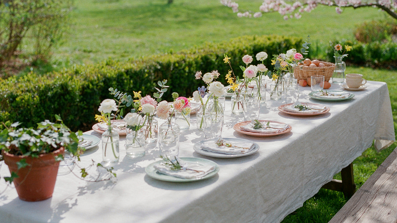 An inviting Easter backyard brunch table set for guests with spring flowers.