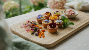 A beautiful assortment of colorful edible flower snacks on a rustic wooden board at a garden party.