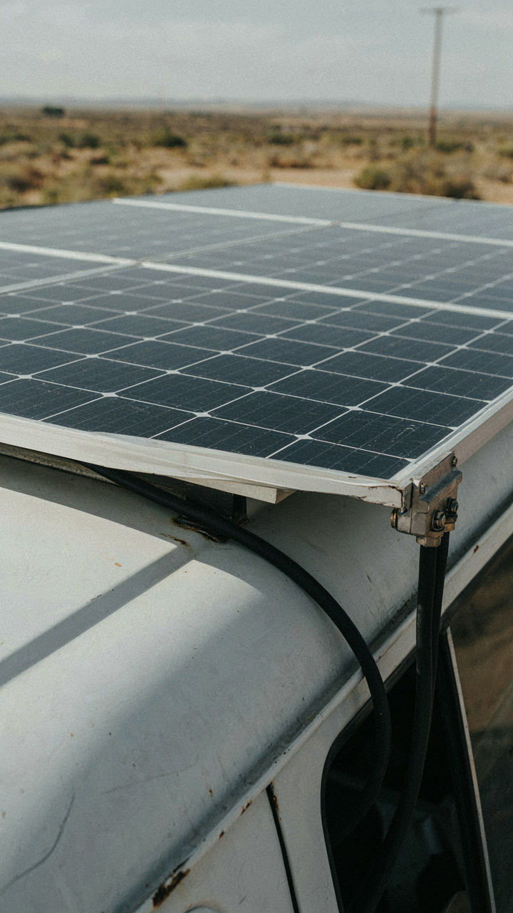 Solar panels on a van roof catch bright sunlight.