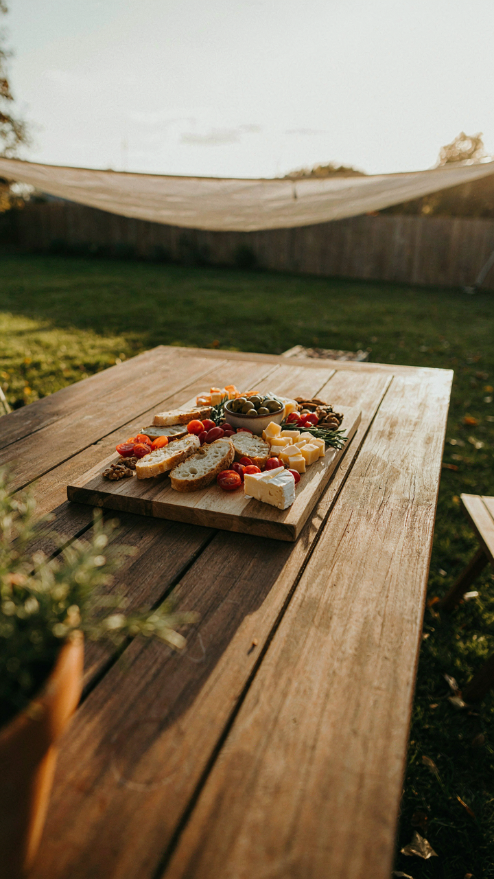 An outdoor snack board is completely covered by a shade sail.