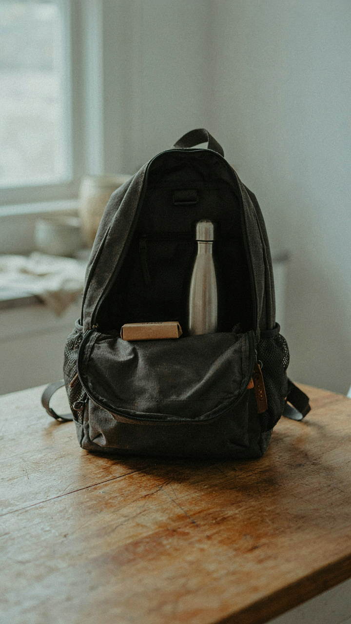 An open backpack shows only a water bottle and a small snack bar.