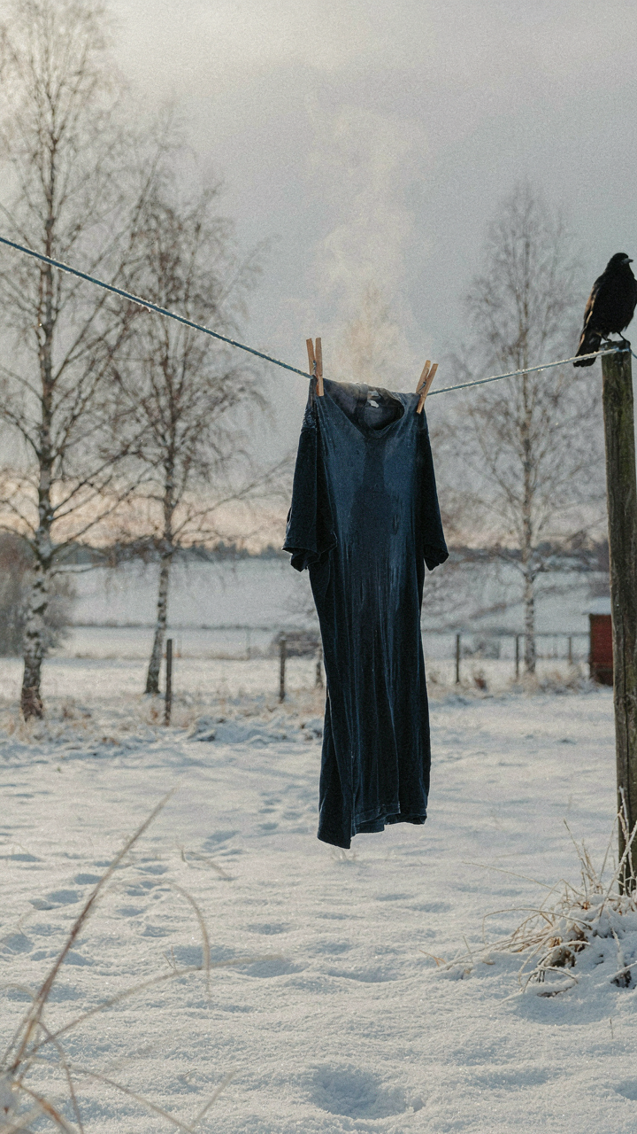 A wet shirt hangs on a line in winter, with steam coming off it.