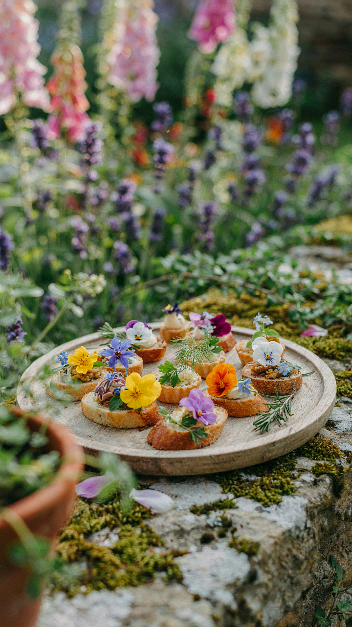 Edible flowers decorating small appetizer bites on a whimsical tray.