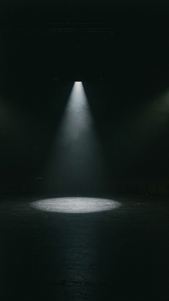 A bright spotlight shines on a dark, empty stage.