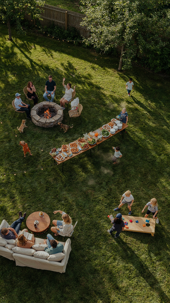 An aerial view of a backyard party with different activity zones and people.