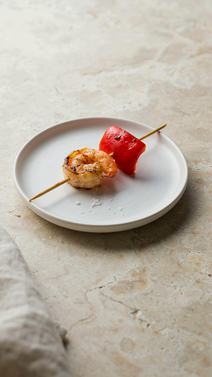 An elegant skewer with two ingredients on a simple white plate.