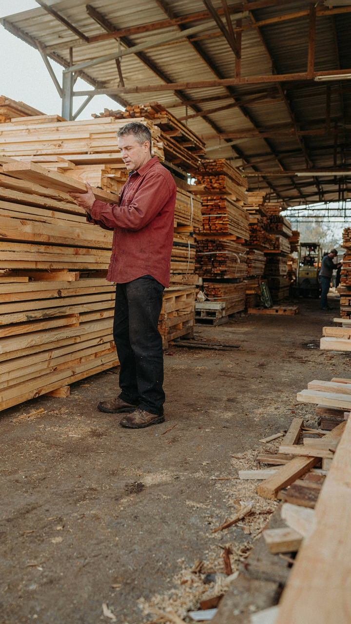A person looks at different types of wood in a lumber yard.