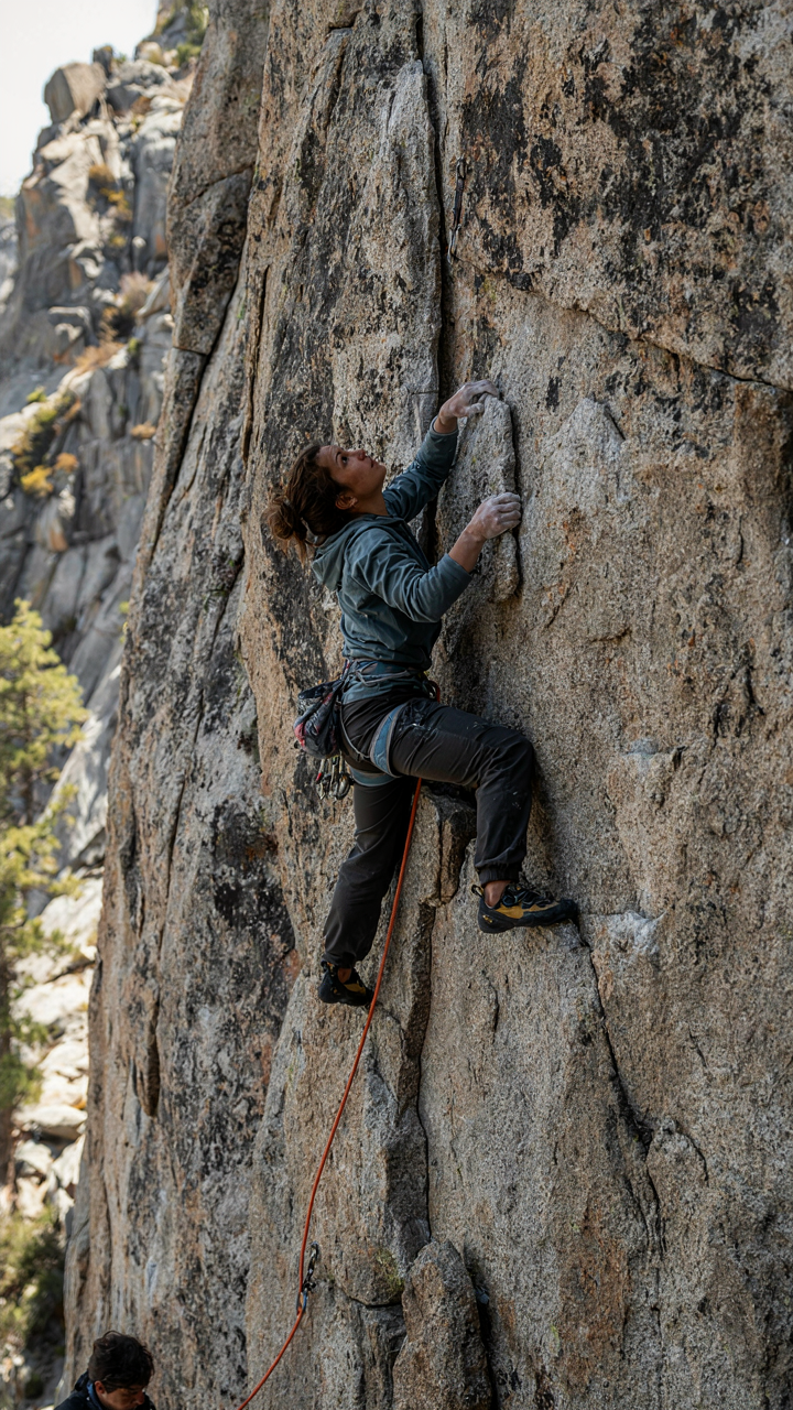 A rock climber uses ropes to ascend a vertical rock face.