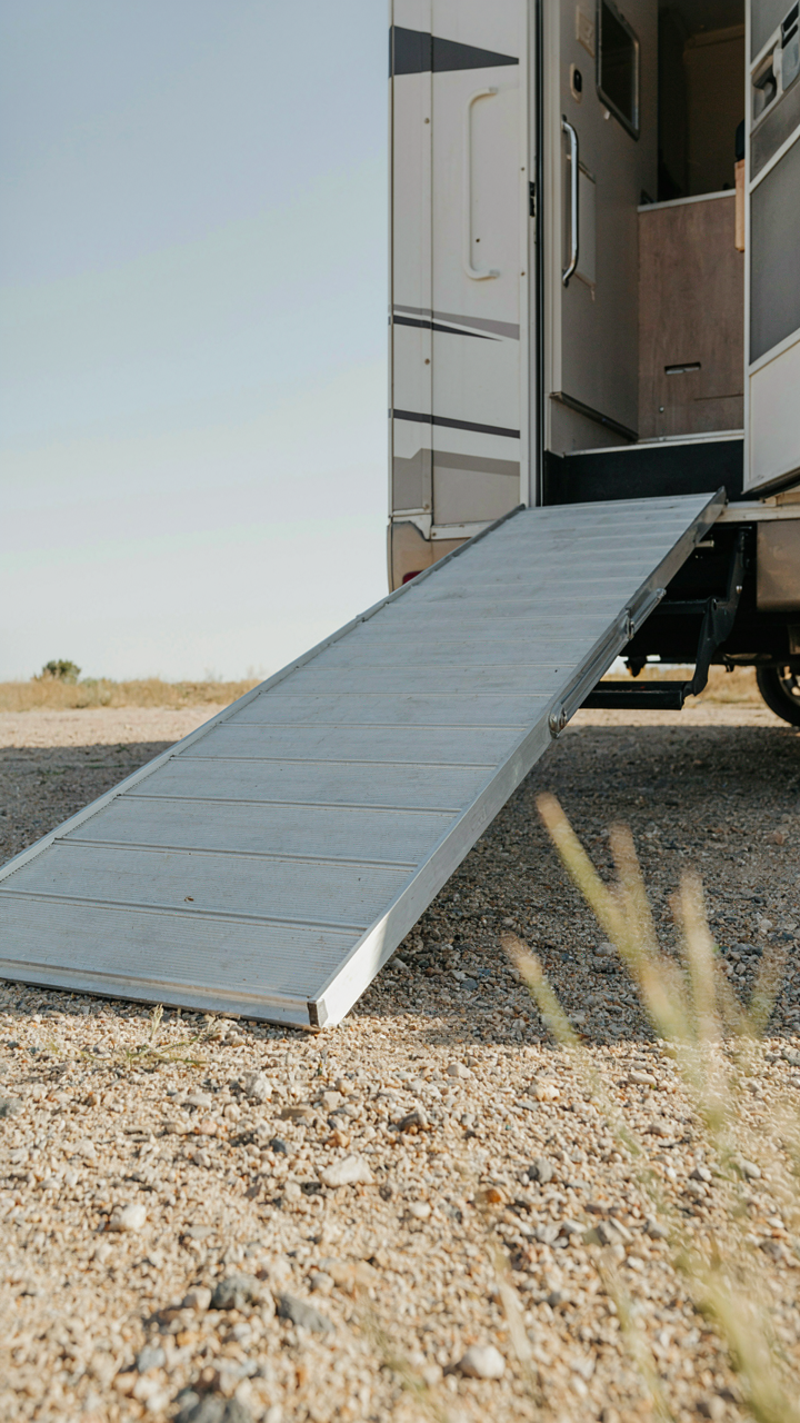 A sloped RV ramp with grooves, designed to use gravity for dirt removal.
