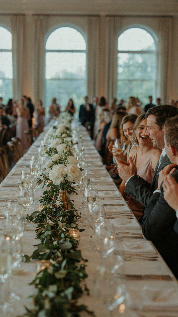 A wedding reception table with a slightly imperfect greenery table garland.