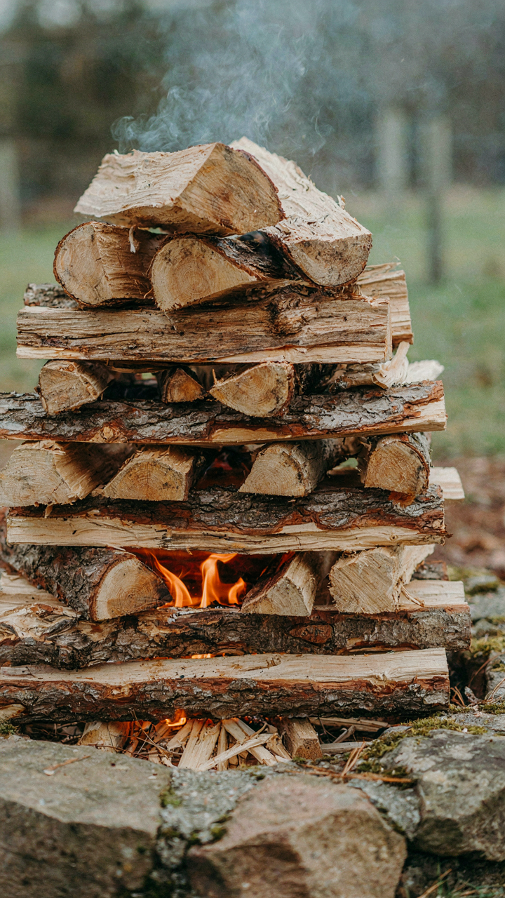 A close-up view of perfectly stacked logs in a fire pit ready for ignition.