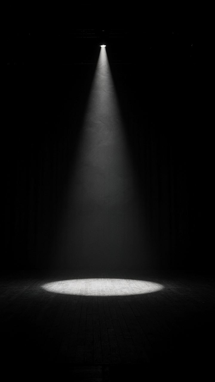 A single spotlight lights up a small part of a stage.