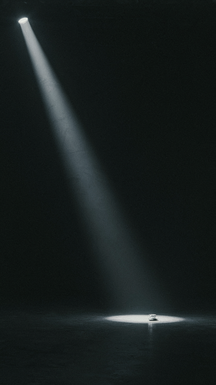 A single spotlight shines on a far away object in darkness.