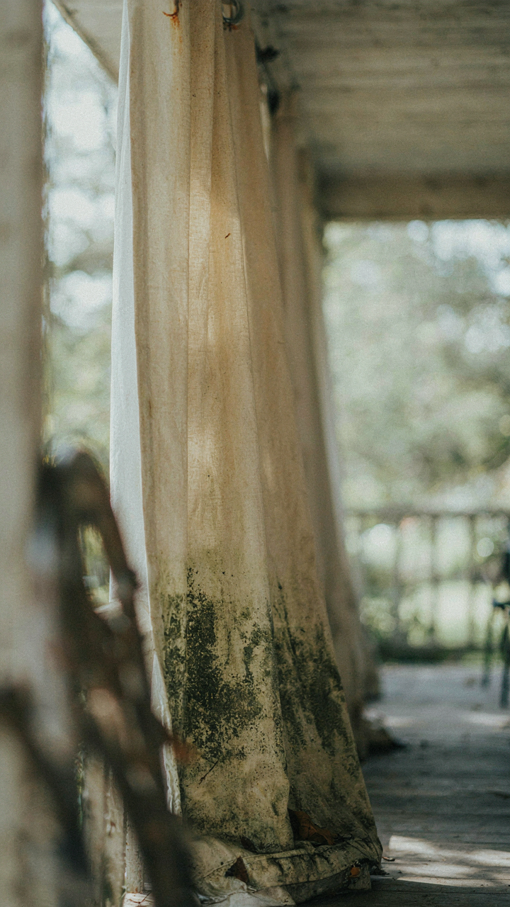 A dirty, moldy outdoor curtain shows signs of neglect and sun damage.